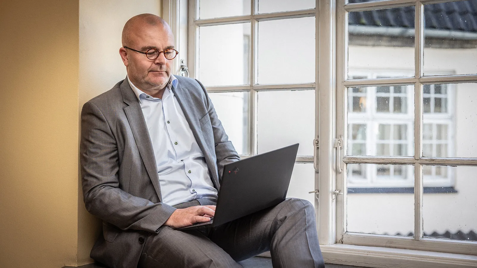 Søren Overbeck arbejder ved sin computer i vindueskarmen
